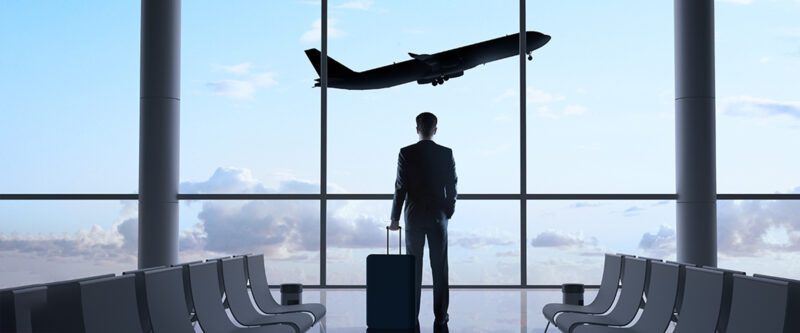 Business Travel Accident Insurance - Business Man at Airport with flying plane in background