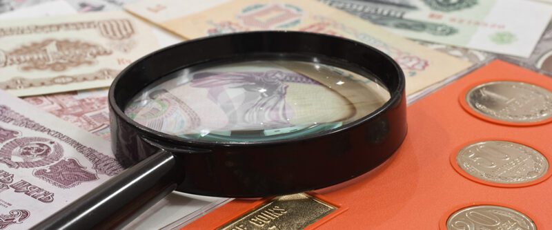 Coins Insurance | Coins and Paper Money under a Magnifying glass.