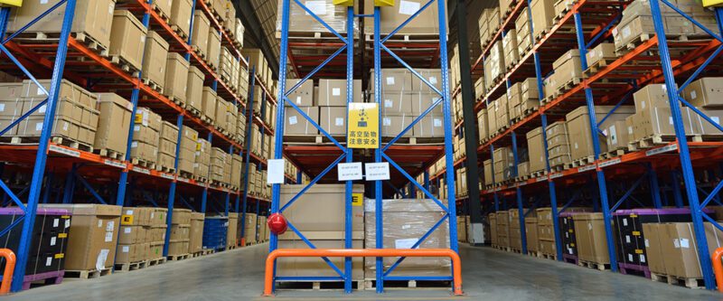 Supply Chain Insurance - Inside Retail Distribution Warehouse - Interior of warehouse with blue metal shelving holding cardboard boxes